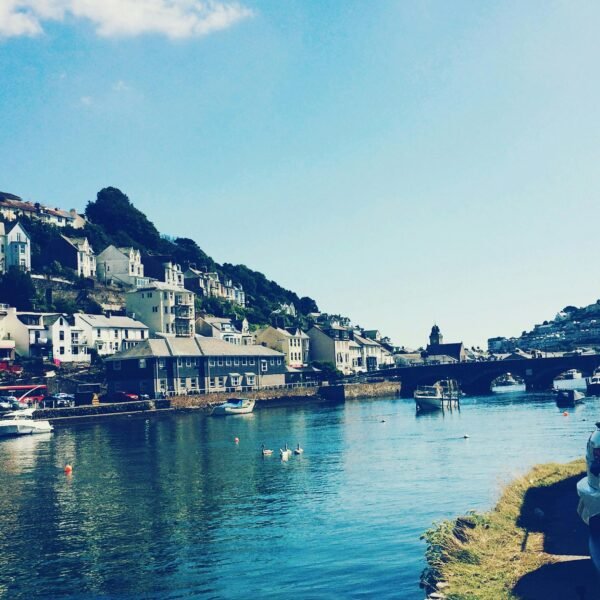 Picturesque view of Looe harbor with boats and houses under a clear sky in England.