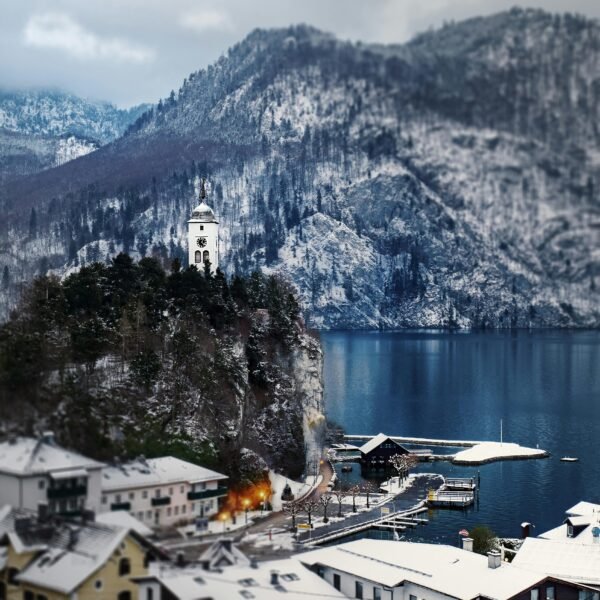 Scenic winter view of Traunkirchen in Austria with snowy mountains and a blue lake.